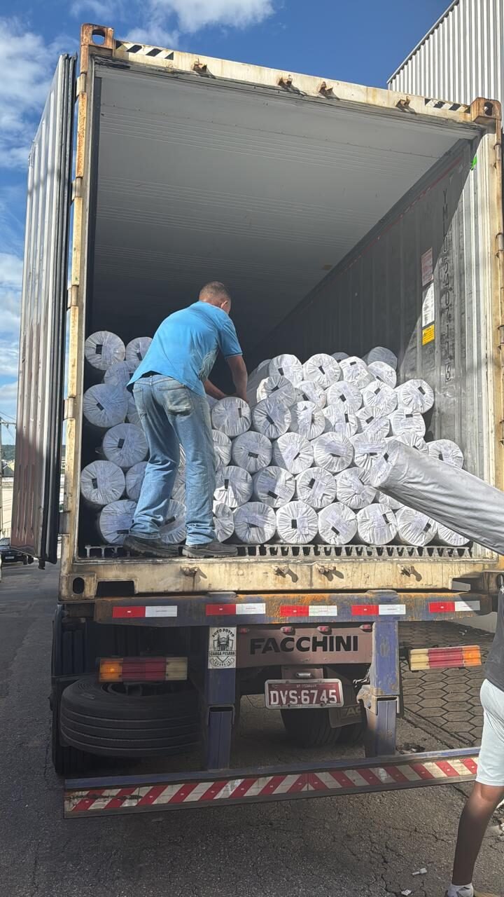 Carga em rolos sendo organizada em container para logística internacional